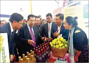  ?? SUPPLIED ?? Prime Minister Hun Sen holds a bottle of passion fruit wine at a fair.