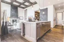  ??  ?? The kitchen has a nine-foot island, stainless steel appliances, granite countertop­s and a metal barn door separating the office/library.