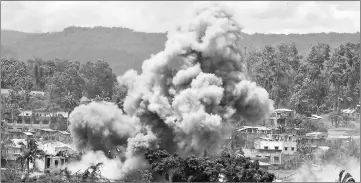  ??  ?? Black smoke billows from burning houses after Philippine airforce attack planes dropped bombs during the an aerial bombing at militant position in Marawi yesterday. — AFP photo