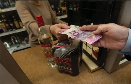  ??  ?? A customer pays for a bottle of vodka and four cans of cider costing £17, which rises to just over £21