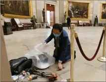  ?? The Associated Press ?? Rep. Andy Kim, D-N.J., cleans up debris and personal belongings strewn across the floor of the Rotunda in the early morning hours of Thursday, after protesters stormed the Capitol in Washington on Wednesday.