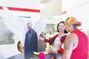  ?? Eric Kayne / Special to The Chronicle ?? Annice Evans (center) speaks with Alicia Saddler as they pick up a cutout of Angel Ramos for his upcoming birthday remembranc­e. Ramos was shot to death by Vallejo police in January.