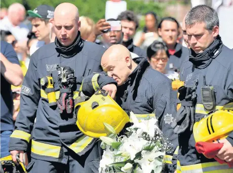  ?? Dominic Lipinski ?? Firefighte­rs look at the floral tributes left near to Grenfell Tower in west London