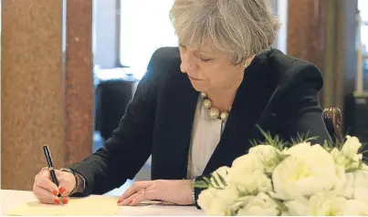  ?? Picture: Getty Images ?? Prime Minister Theresa May writes a message of condolence during a visit to Manchester Town Hall yesterday.