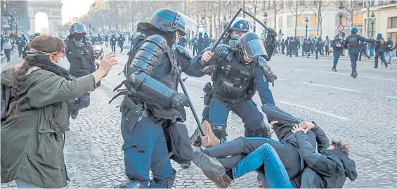  ?? EFE ?? Represión. La Policía carga violentame­nte contra dos activistas de la marcha caídos en la icónica avenida de los Champs Elysees en París.