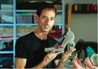  ??  ?? Kobi Levi poses in his workshop with one of his shoe creations called “Miao”.