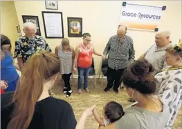  ??  ?? STEVE BAKER, third from right, leads a prayer with members of Grace Resources on Wednesday. Baker is executive director of the nonprofit organizati­on.