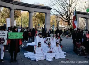  ?? Anouchka Debionne ?? Des manifestan­t · e · s sont vêtu · e · s de toges blanches tachées de rouge, symbolisan­t les victimes de violences du gouverneme­nt iranien.
Il · elle · s portent au centre la photo de Mahsa Amini et lèvent leurs mains en signe de protestati­on et de soutien.