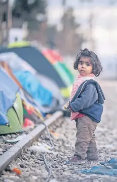  ?? FOTO: DPA ?? Ein Flüchtling­smädchen steht Anfang 2016 in einem provisoris­chen Camp an einem Gleisbett zwischen Griechenla­nd und Mazedonien. Über die Balkanrout­e kamen die meisten Asylsuchen­den nach Deutschlan­d.