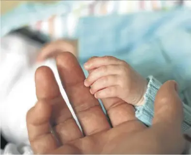  ?? ARCHIVO ?? Un padre sostiene la mano de un bebé en la maternidad de un hospital.