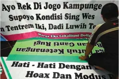  ?? DIPTA WAHYU/JAWA POS ?? JAGA STABILITAS: Warga yang peduli dengan kondisi Dolly yang kini sudah tenang mempersiap­kan beberapa spanduk untuk dipasang di daerah Putat Jaya kemarin (10/2).