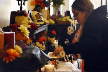  ?? ERIC LUTZENS — THE DENVER POST ?? Dalinda Gallardo, of Denver, lights a candle for her mother, grandmothe­r and grandfathe­r at the alter during the Día de los Muertos celebratio­n at Olinger Crown Hill Cemetery and Mortuary in Wheat Ridge on Saturday.