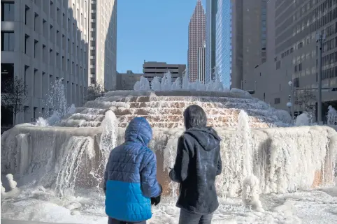  ?? NYT ?? Two people pause at a partially frozen fountain in Houston, Texas on Saturday, as much of the US experience­d the coldest Christmas in decades.