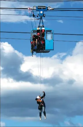  ?? MARCEL KUSCH / DPA VIA AFP ?? Fire crews rescue a mother and child from a gondola over the Rhine River in Cologne, Germany, on Sunday. Crews evacuated as many as 100 passengers from suspended cable cars after a gondola ran into a support pillar. No injuries were reported.