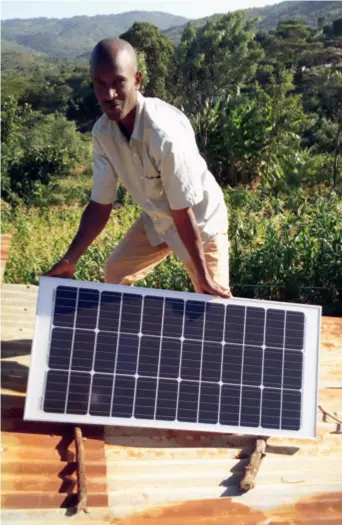  ??  ?? James Musau installs a solar panel on the roof of a client’s house in Wautu Village, Makueni County