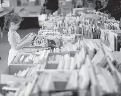  ?? ADRIAN LAM, TIMES COLONIST ?? Alliana Howson peruses the kids’ section during the Times Colonist Book Sale at the Victoria Curling Club last Sunday. An early start on reading is invaluable for young people’s vocabulari­es and fluency, Geoff Johnson writes.