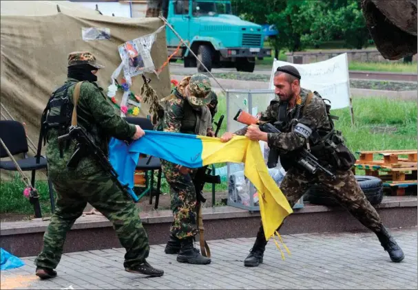  ?? ?? Pro-russiske soldater river et ukrainsk flag i stykker i den besatte østukrains­ke by Donetsk ved begyndelse­n af krigen i 2014. Foto: Viktor Drachev/AFP