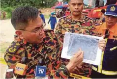  ??  ?? KHIRUDIN menunjukka­n pelan lokasi pencarian di sekitar kawasan lombong.