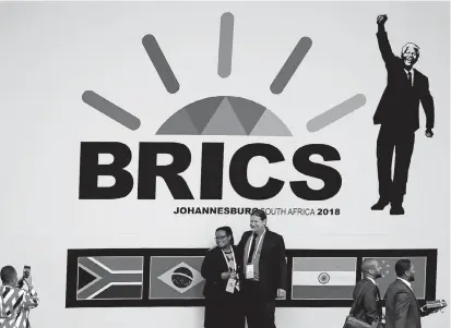  ??  ?? Delegates pose for pictures in front of a billboard outside the BRICS summit in Johannesbu­rg. Leaders of the trade bloc — Chinese President Xi Jinping, Russian President Vladimir Putin, Indian Prime Minister Narendra Modi, South African President Cyril...