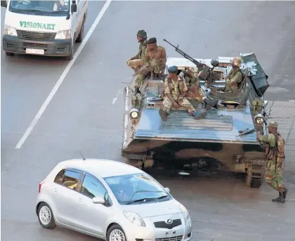  ?? Pictures / AP ?? Soldiers man their position with a military vehicle outside the office of President Robert Mugabe, in Harare. Mugabe and his wife Grace are said to be under house arrest.