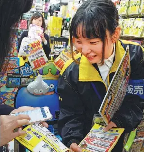  ?? MA PING / XINHUA ?? A supermarke­t employee explains what categories of products will get a discount, if paid through Alipay, in Tokyo, before the Double 12 (Dec 12) shopping spree.