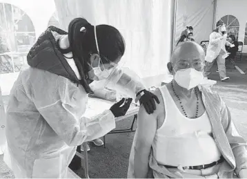  ?? HAVEN DALEY/AP ?? Victor Villegas, 78, right, receives a COVID-19 vaccine from a health care worker Monday at a vaccinatio­n site in San Francisco. The city is reserving some vaccines for seniors in the two ZIP codes hit hardest by the pandemic.