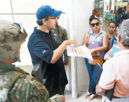  ?? NELLY SALAS ?? Un elemento de la PGR explica el procedimie­nto a seguir a afectados reunidos en la empresa de resguardo.