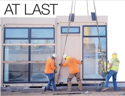  ?? JEFF GRITCHEN/ORANGE COUN TY REGISTER ?? Workers help align a shipping container as it is lowered in place at Potter’s Lane in Midway City, Calif. It takes three containers to make up a 480-square-foot apartment.