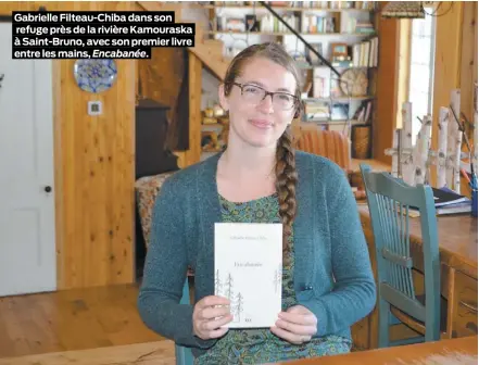  ??  ?? Gabrielle Filteau-Chiba dans son refuge près de la rivière Kamouraska à Saint-Bruno, avec son premier livre entre les mains, Encabanée.