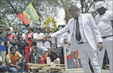  ?? Photograph­s by Matias Delacroix Associated Press ?? JIMMY CHERIZIER, a police-officer-turned-gang-leader, prepares to light a bonfire during a ceremony in July to demand justice for slain Haitian President Jovenel Moise, who had the support of the U.S. government.