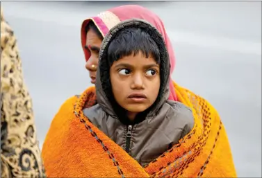  ?? REUTERS ?? A boy and a woman are wrapped in a shawl as they sit at a bus terminal on a cold winter morning in New Delhi, on Friday.