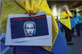  ?? ODED BALILTY/AP ?? A protester holds a banner depicting a bloodthirs­ty Russian President Vladimir Putin during a pro-ukraine demonstrat­ion outside the Russian Embassy in Tel Aviv, Israel, last month. The sign in Russian reads “get out of Ukraine.”