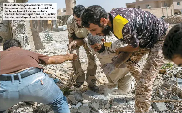  ??  ?? Des soldats du gouverneme­nt libyen d’union nationale viennent en aide à un des leurs, blessé lors de combats contre l’État islamique dans un quartier chaudement disputé de Syrte.