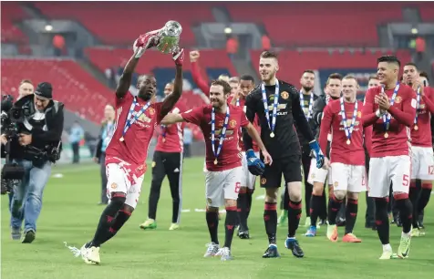  ?? — Reuters ?? Manchester United’s Eric Bailly celebrates with the trophy and team-mates at the end of the match.