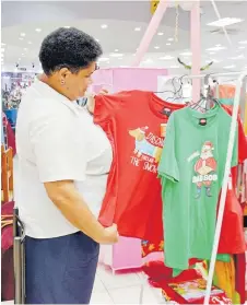  ?? Picture: SOPHIE RALULU ?? Frances Gavidi checks out the Christmas T-shirts at Courts Samabula.