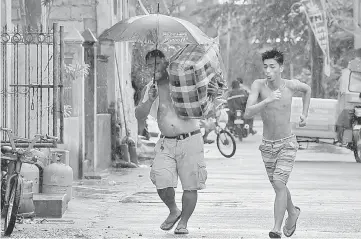  ??  ?? A resident carries his belongings to a safer place while another runs as rains started to pour, with Typhoon Mangkhut approachin­g the city of Tuguegarao, Cagayan province, north of Manila. — AFP photos