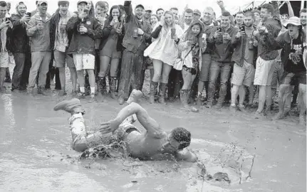  ?? KARL MERTON FERRON/BALTIMORE SUN ?? Egged on by the crowd circled around him, Ryan Bradshaw of Columbia dives into a mud pit in the infield at Pimlico.