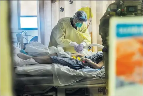  ?? GINA FERAZZI Los Angeles Times ?? DR. MICHAEL MATUS checks on a COVID- 19 patient Tuesday at Loma Linda University Medical Center in Loma Linda, Calif. In the last week, the disease has killed more than 1,500 people in California — nearly 7% of the state’s 22,000- plus total COVID- 19 fatalities.