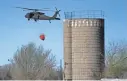  ?? ORLIN WAGNER/AP ?? A National Guard helicopter carries water from a farm pond Tuesday near Hutchinson, Kansas, to fight a deadly wildfire.
