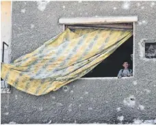  ??  ?? Ein Junge blickt aus einem Fenster in der zerstörten Stadt Duma. Foto: Hummam Sheikh Ali/dpa