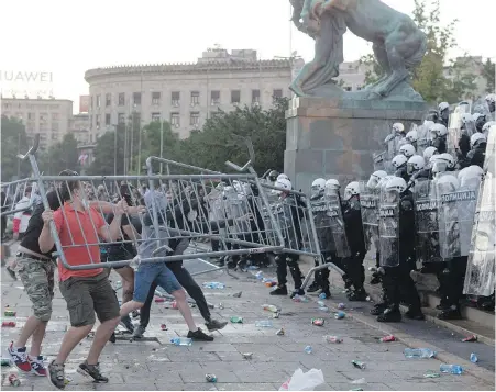  ??  ?? Protesters throw barricade fencing at riot police in the Serbian capital, Belgrade, on Wednesday. Police fired tear gas at protesters in scenes reminiscen­t of the era of late strongman Slobodan Milosevic in the 1990s.