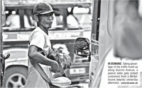  ?? CHRISTIAN MARK LIM ?? IN DEMAND. Taking advantage of the traffic build-up along Quirino Avenue, a peanut seller gets instant customers from a Mintalboun­d jeepney yesterday afternoon.