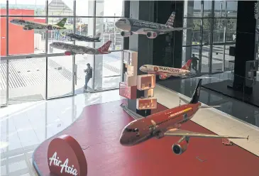  ??  ?? Model aircraft hang in the lobby of the AirAsia headquarte­rs in Sepang, Malaysia.