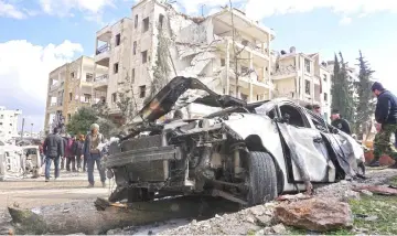  ??  ?? The wreckage of a car and a damaged building in the background are seen in Syria’s jihadist-held city of Idlib following a double bomb attack.