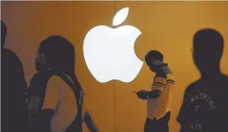  ?? Reuters-Yonhap ?? A man looks at the screen of his mobile phone in front of an Apple logo outside a store in Shanghai. Apple’s new iPhone X will go on sale Nov. 3.