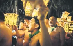  ?? ?? SHINING EXAMPLES. Men carry lanterns as they walk to a river to cleanse their bodies during the Sominsai Festival.