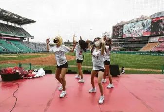  ?? Chung Sung-Jun / Getty Images ?? The masked cheerleade­rs at Happy Dream Ballpark in Incheon, South Korea, didn’t appear to mind that they were performing for an audience consisting of zero fans Tuesday.