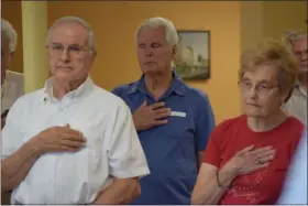  ?? MARIAN DENNIS — MEDIANEWS GROUP ?? Guests at the pinning ceremony held at the TriCounty Active Adult Center in Pottstown hold their hands over their hearts as the ceremony comes to a close with the playing of Taps.