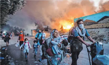  ?? ARCHIVFOTO: PETROS GIANNAKOUR­IS/DPA ?? Menschen fliehen im September 2020 vor einem erneuten Feuer aus dem Flüchtling­slager Moria. Zuvor hatten bereits mehrere Brände das Lager nahezu vollständi­g zerstört.