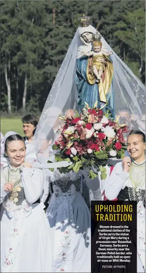  ??  ?? Women dressed in the traditiona­l clothes of the Sorbs carry the statue of Virgin Mary during a procession near Rosenthal, Germany. Sorbs are a Slavic minority near the German-Polish border, who traditiona­lly hold an openair mass on Whit Monday.